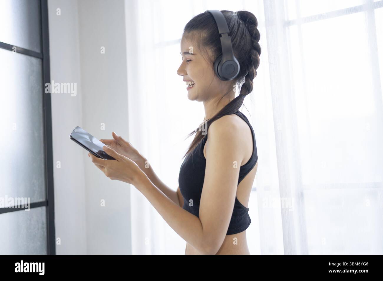 Fitness donna asiatica che utilizza smartphone e cuffie si diverte ad ascoltare musica. Donna con cuffie per smartphone dopo l'allenamento Foto Stock
