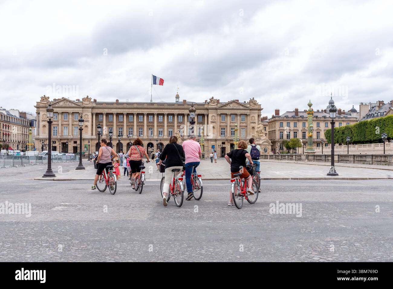 Parigi, Francia, 06.23.25. Guida con turisti in bicicletta in Place de la Concorde di fronte all'Hotel de la Marine nell'8° arrondissement di Parigi Foto Stock