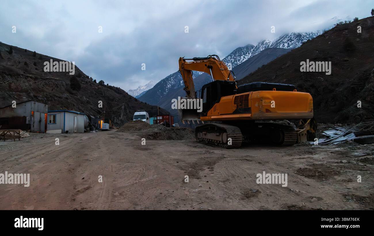 Escavatore in cantiere nella regione montuosa in tarda serata Foto Stock