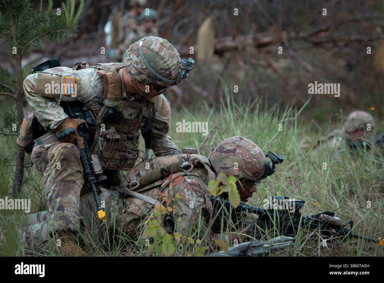 Un soldato degli Stati Uniti assegnato alla compagnia Alpha, 1st Battalion, 125th Infantry Regiment, Michigan National Guard controlla lo stato di un compagno di squadra durante l'addestramento React-to-contact presso la Ādaži Training area, Lettonia, l'8 giugno 2025. Il soldato conduce un rapporto simulato di PIZZO e una valutazione delle vittime mentre partecipa a un'esercitazione di fuoco vivo progettata per migliorare la comunicazione sul campo di battaglia e le tattiche di piccole unità in coordinamento con i partner della NATO. (Foto U.S. Air National Guard di Tech. Sergente Bethany Rizor) Foto Stock