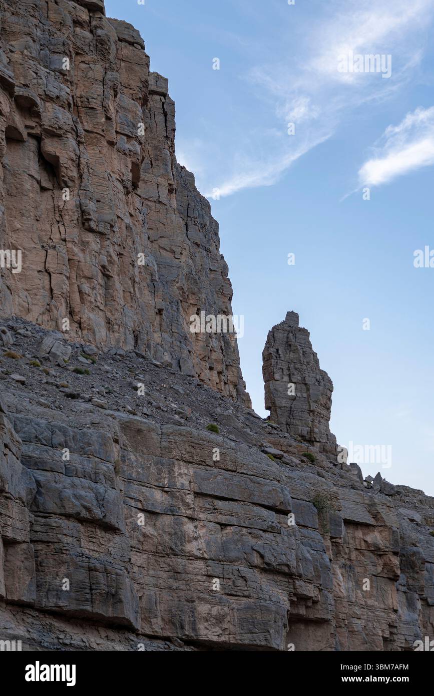 Alte torri di pietra calcarea erosa e pareti rocciose con formazioni sedimentarie stratificate, località Oman, Musandam. Foto Stock