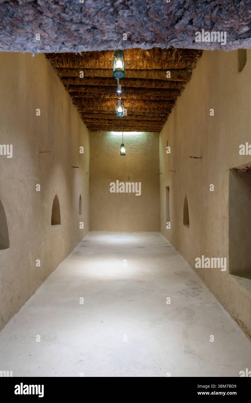 Un lungo corridoio con pareti bianche e travi a soffitto in legno è illuminato da luce naturale al forte al Jahili di al Ain negli Emirati Arabi Uniti. Foto Stock