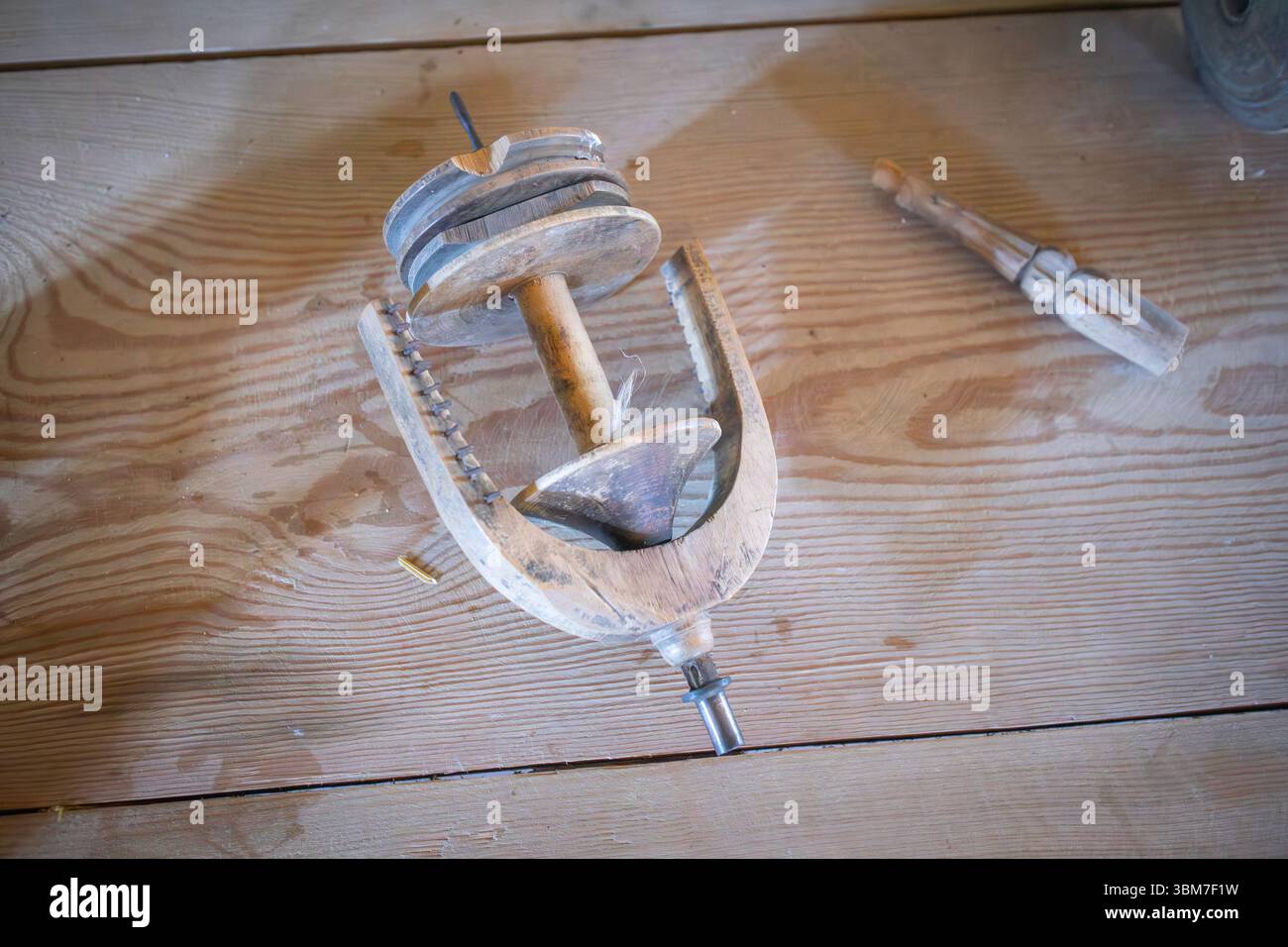 Un oggetto di legno con un foro nel mezzo siede su un tavolo di legno. L'oggetto è uno strumento utilizzato per uno scopo specifico. Il tavolo è fatto di legno Foto Stock