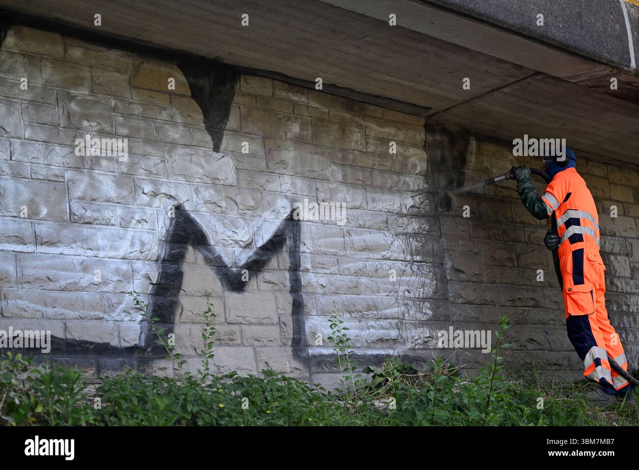 Essen, Germania. 25 giugno 2025. David Brown rimuove i graffiti con una sabbiatrice a bassa pressione. I graffiti vengono rimossi con una sabbiatrice a Löwental nell'Essen-Werden. Crediti: Federico Gambarini/dpa/Alamy Live News Foto Stock