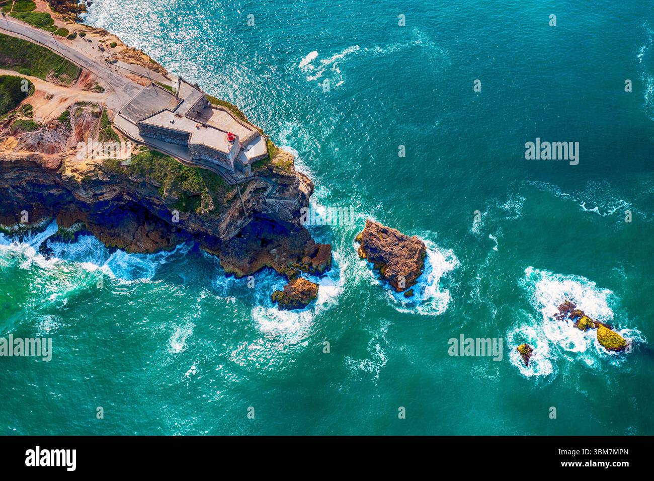 Rocky Cape con un faro nella città di Nazare in Portogallo sulle rive dell'Oceano Atlantico Foto Stock