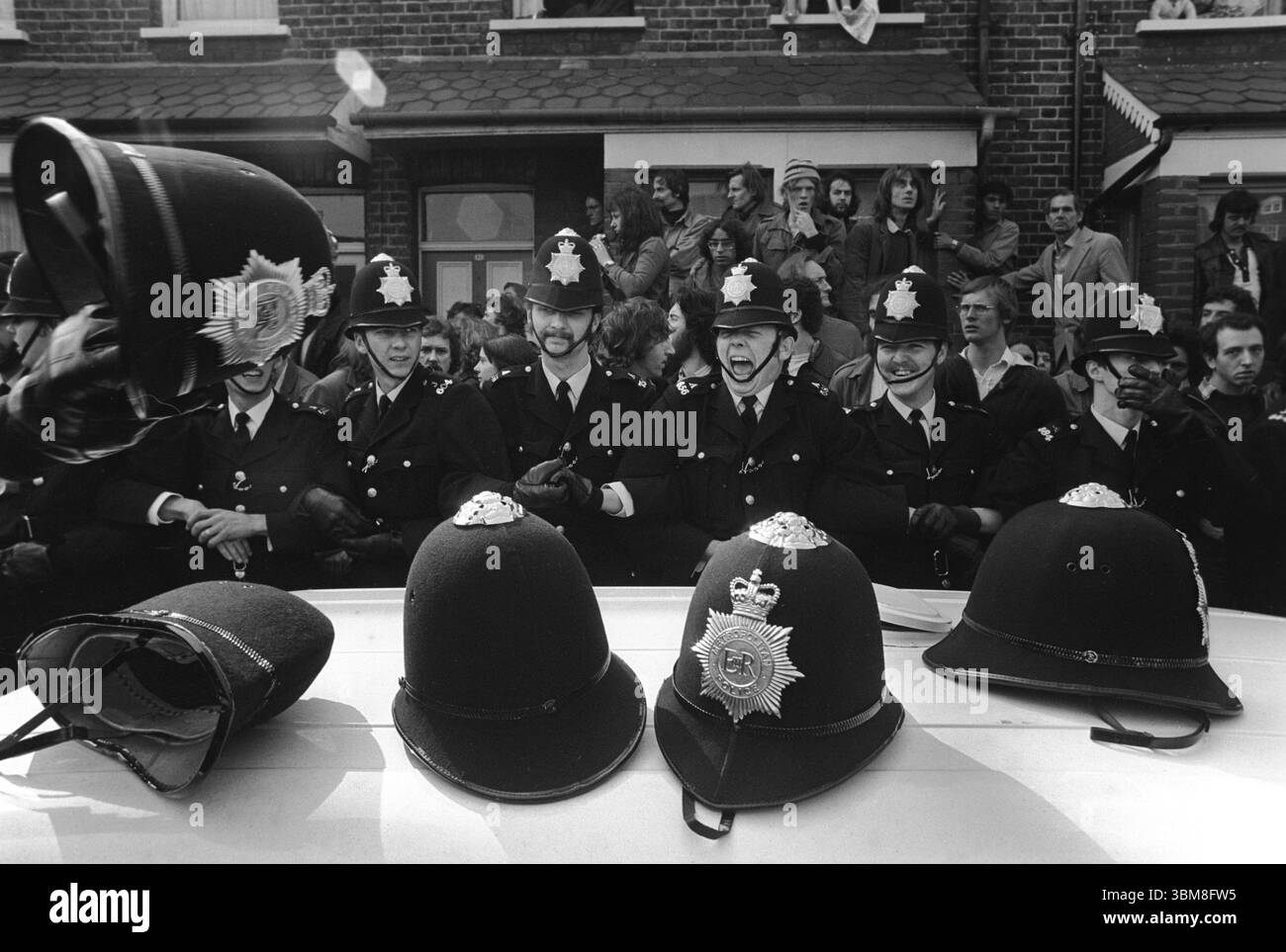 I caschi dei poliziotti sono caduti a terra durante le grinze con picchetti e posizionati sulla parte superiore di un tetto di lattine. I collegamenti della polizia per le armi frenano i manifestanti. Sciopero di Grunwick e disputa industriale. Willesden, Londra, Inghilterra anni '1977 1970 UK HOMER SYKES Foto Stock I caschi dei poliziotti sono caduti a terra durante le grinze con picchetti e posizionati sulla parte superiore di un tetto di lattine. I collegamenti della polizia per le armi frenano i manifestanti. Sciopero di Grunwick e disputa industriale. Willesden, Londra, Inghilterra anni '1977 1970 UK HOMER SYKES Foto Stock