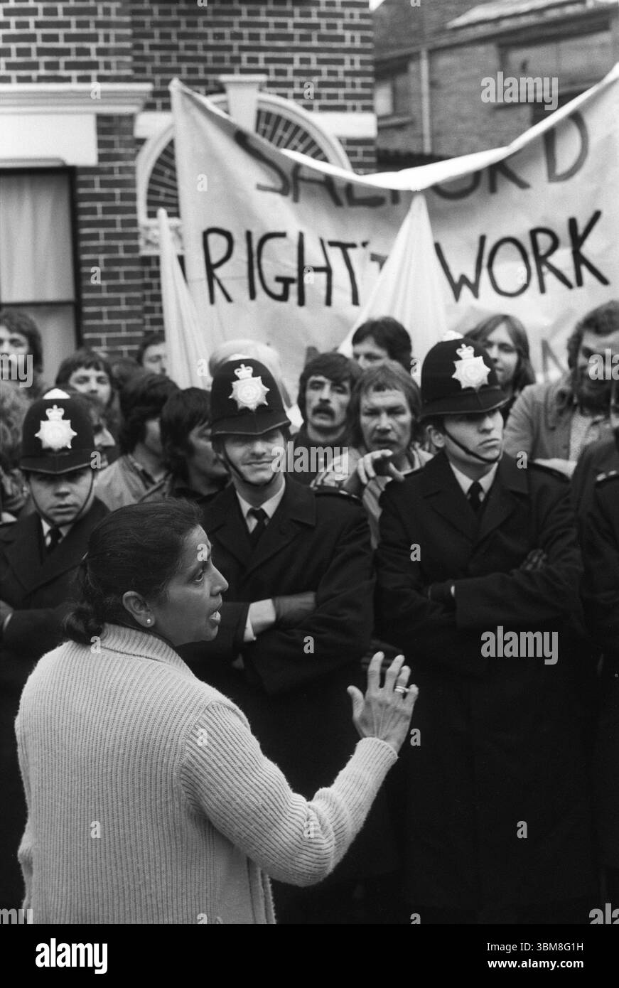 L'onorevole Jayaben Desai si rivolge ai manifestanti dietro una linea di polizia. Ha guidato un gruppo di donne prevalentemente asiatiche che protestavano con i manifestanti sindacali di sinistra contro i bassi salari e le cattive condizioni di lavoro e non gli è stato permesso di aderire a un sindacato presso il Grunwick Film Processing Laboratory. Willesden, Londra, Inghilterra anni '1977 1970 UK HOMER SYKES Foto Stock