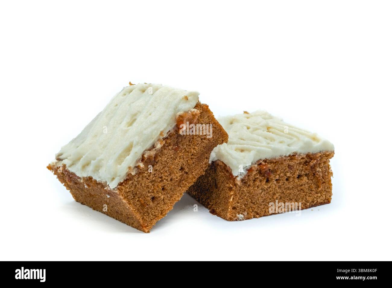 Due pezzi di torta di carote inumiditi con glassa di vaniglia su sfondo bianco concetto di caramelle naturali. Foto Stock