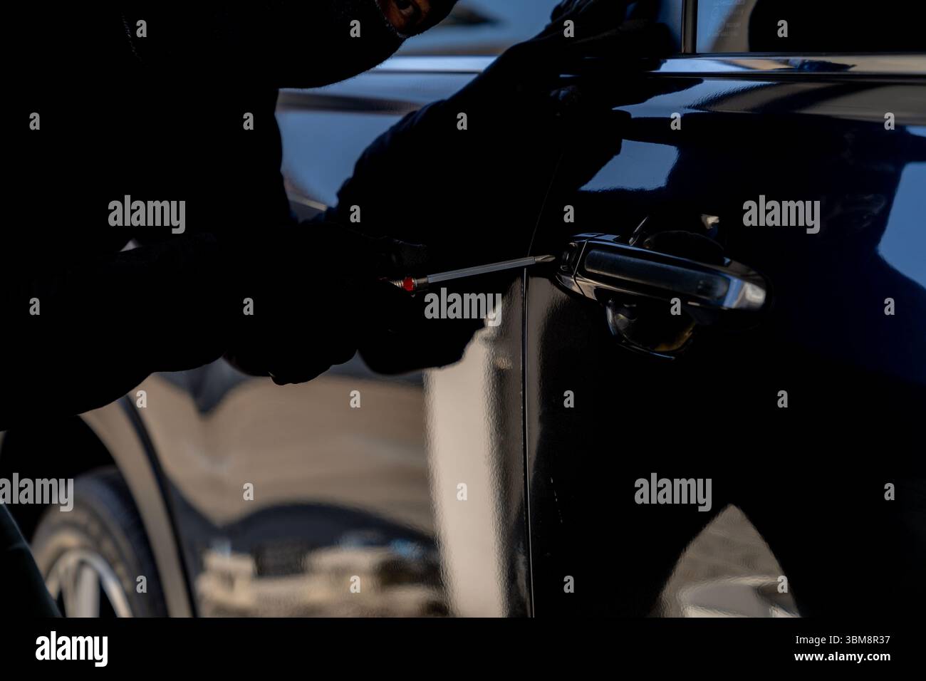 Tentativo criminale di irrompere in un'auto parcheggiata, evidenziando i rischi di furto del veicolo e problemi di sicurezza. Foto Stock Tentativo criminale di irrompere in un'auto parcheggiata, evidenziando i rischi di furto del veicolo e problemi di sicurezza. Foto Stock