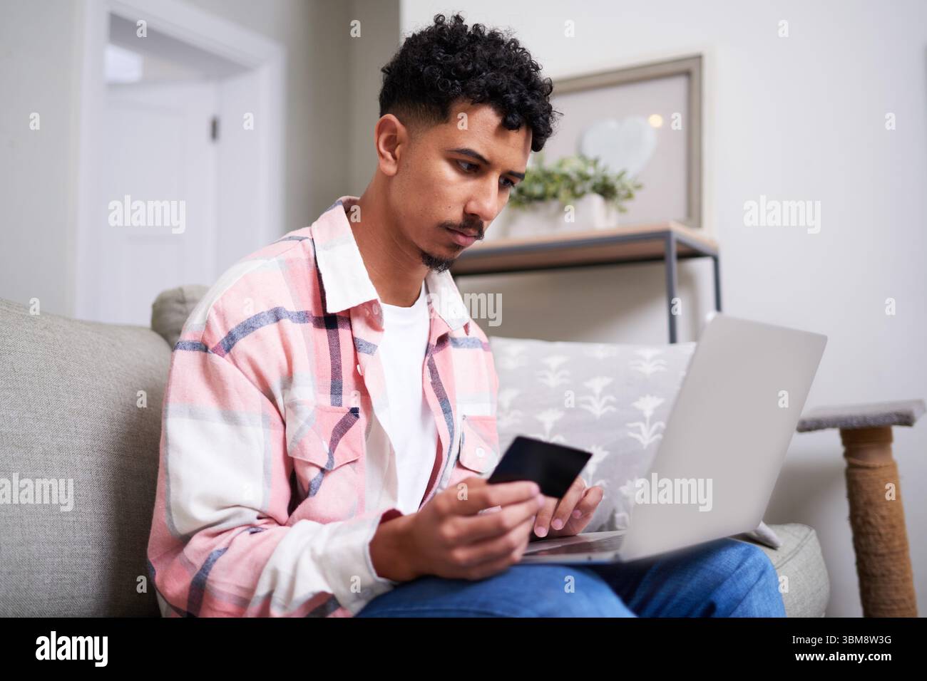 Persona che fa acquisti online a casa con carta di credito e laptop Foto Stock