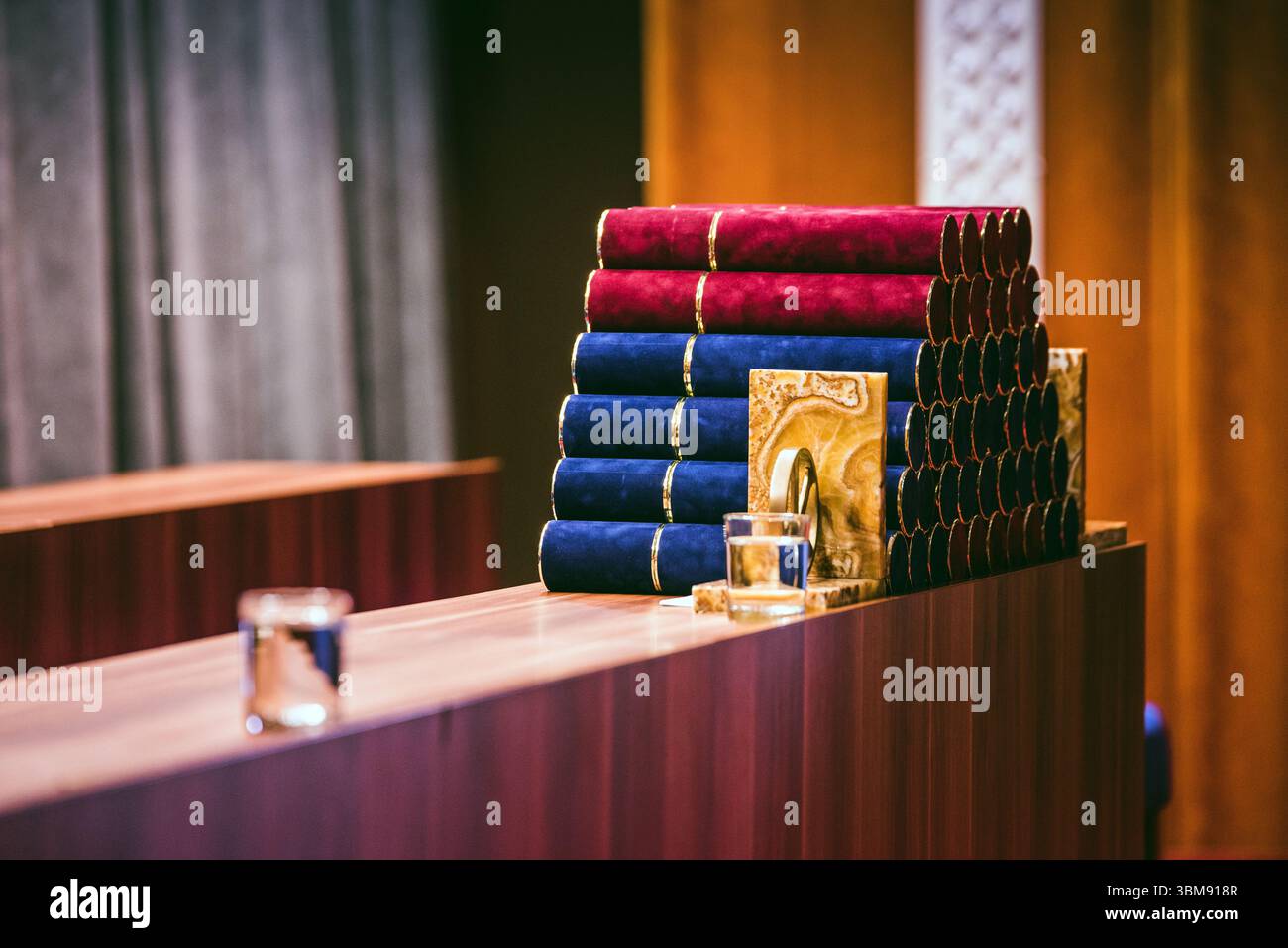 Illustrazione della cerimonia di laurea: Coperture di diploma in rosso e blu posizionate ordinatamente su un tavolo nell'auditorium, preparate per gli studenti laureati. Foto Stock