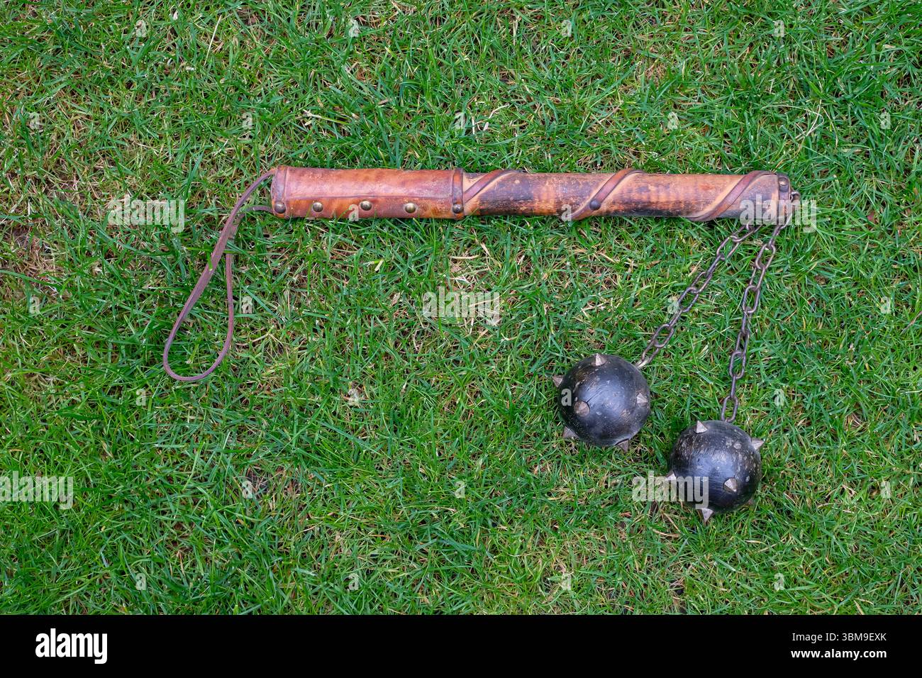 L'arma decorativa medievale o la mazza Morgenstern con punte giace sull'erba verde. Arti marziali e tornei. Foto Stock