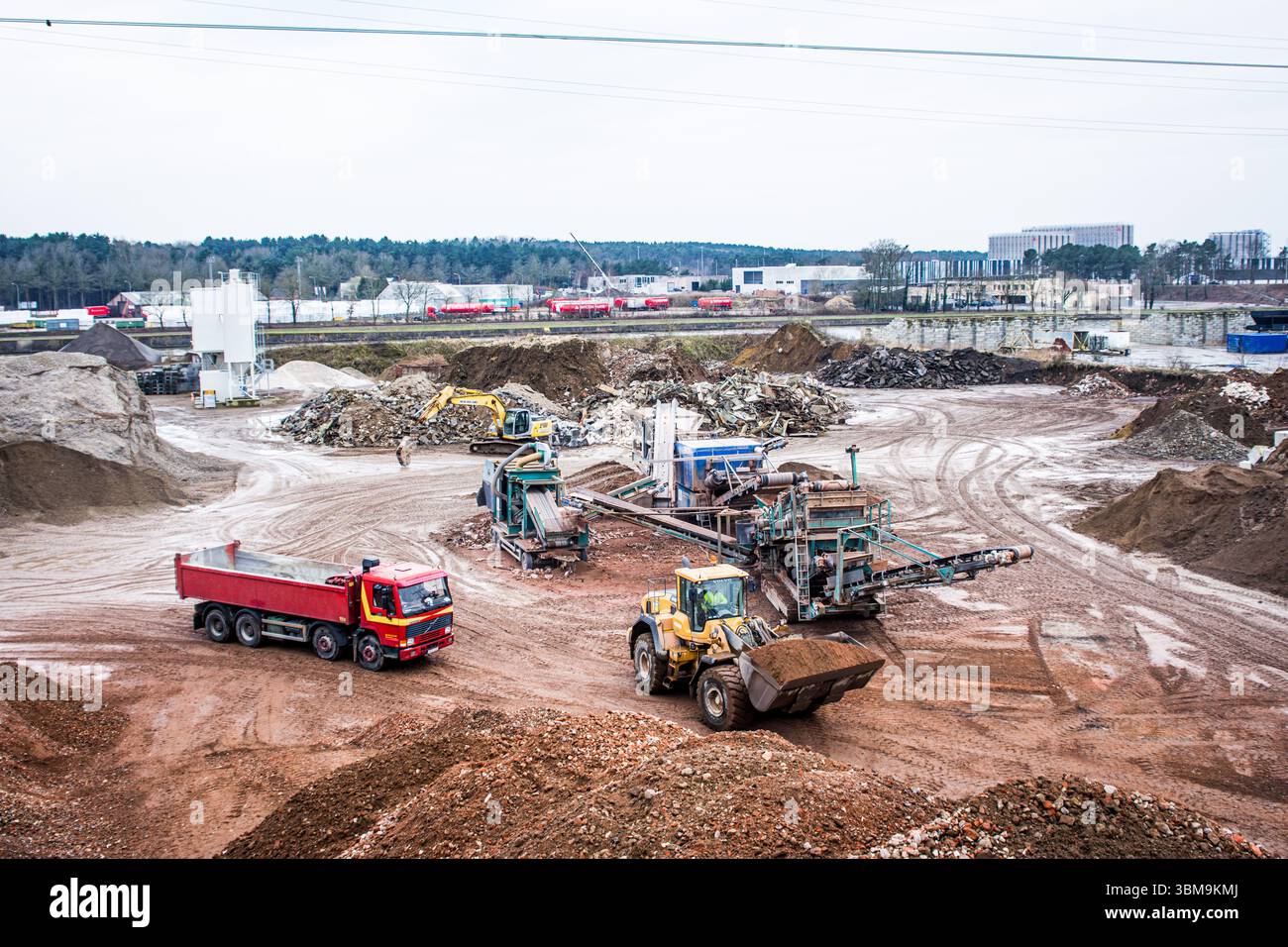 Cantiere industriale su larga scala che mostra le attrezzature di movimento terra, i dumper e i macchinari per la lavorazione dei materiali in funzione. Foto Stock
