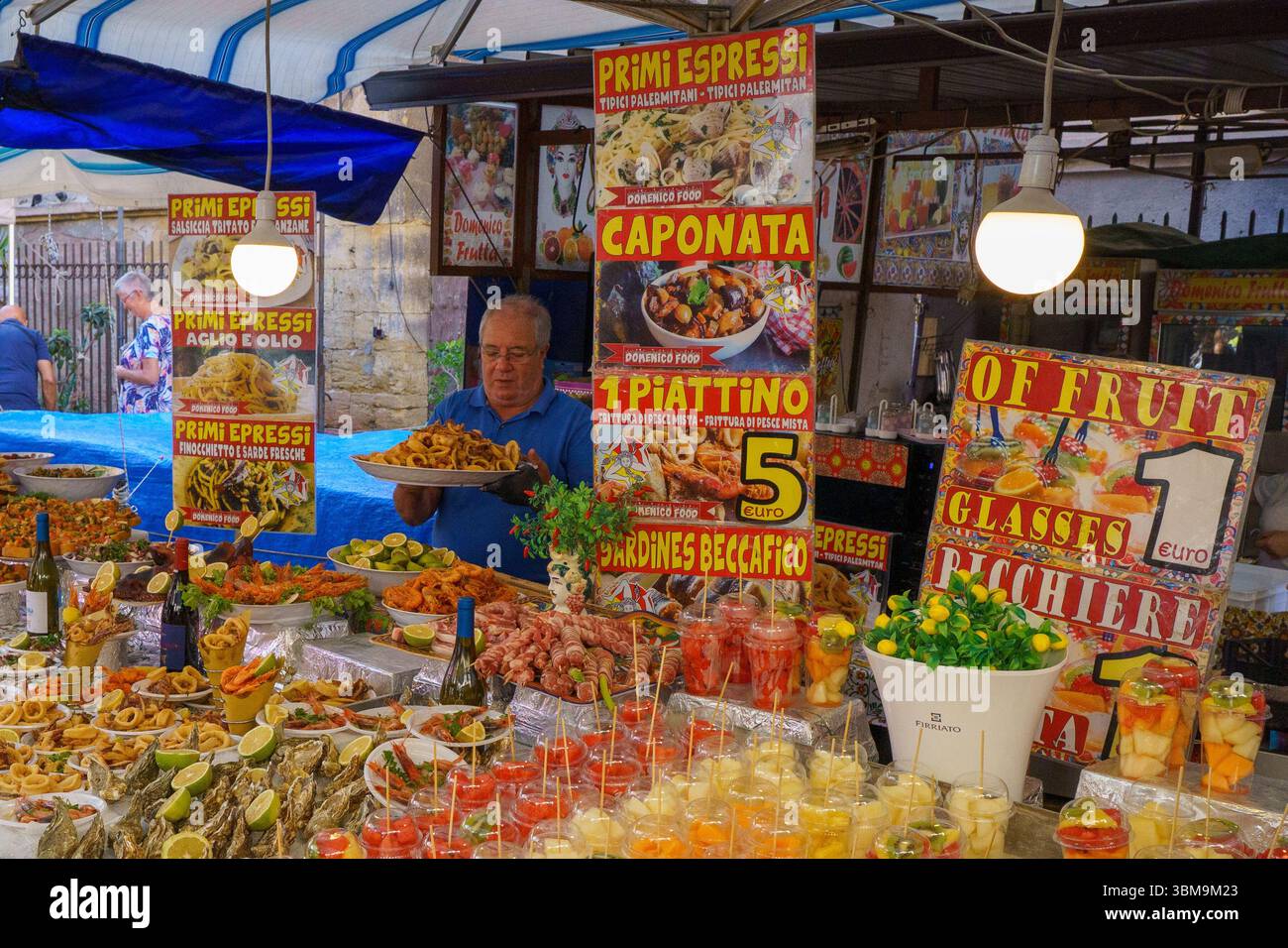 Questa immagine cattura l'atmosfera vivace e saporita del mercato di Ballarò a Palermo, in Sicilia. Una varietà di bancarelle all'aperto mostrano prodotti freschi e colorati Foto Stock