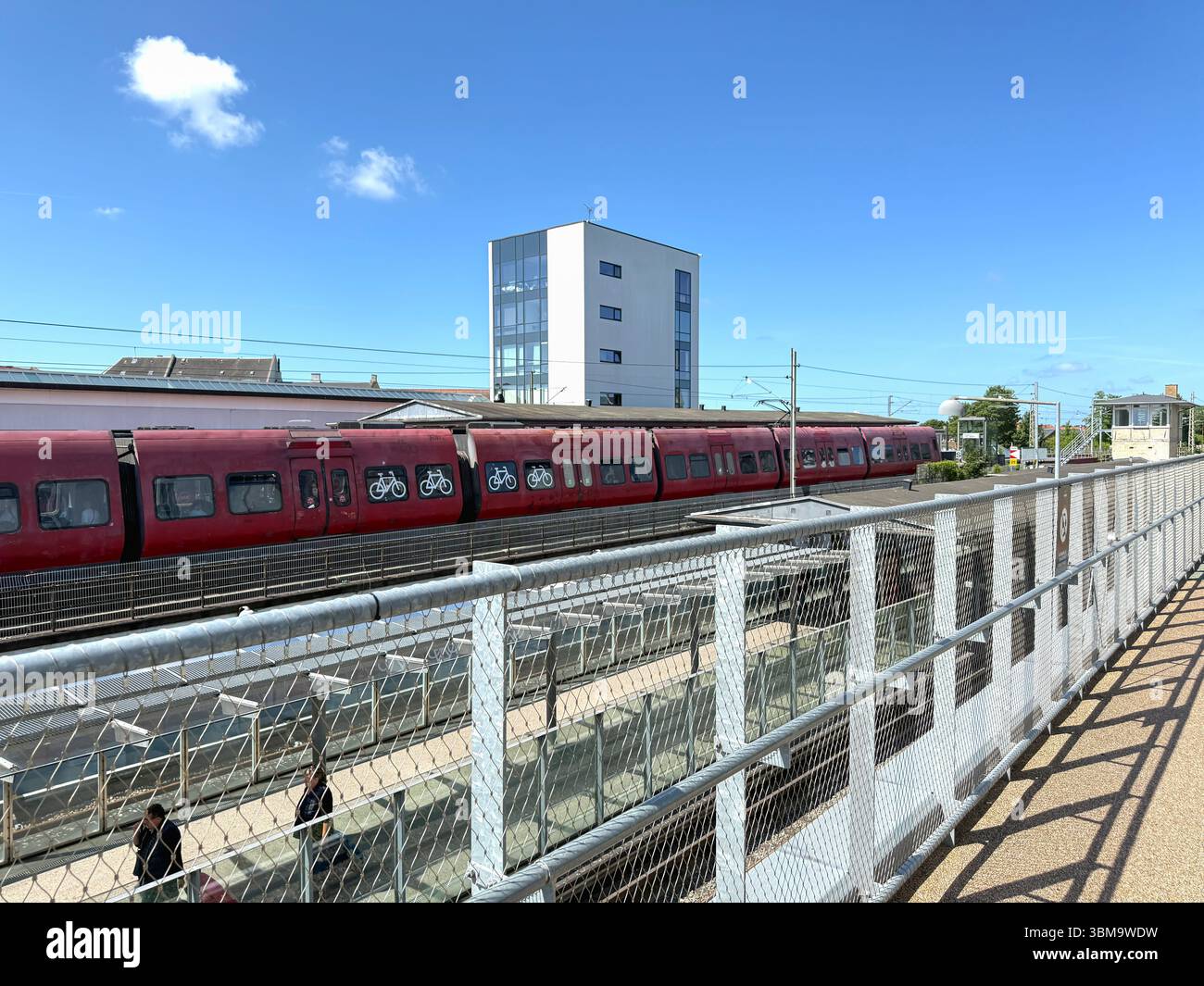 Lungo treno rosso alla banchina della stazione. Copenaghen, Danimarca - 25 giugno 2025 Foto Stock