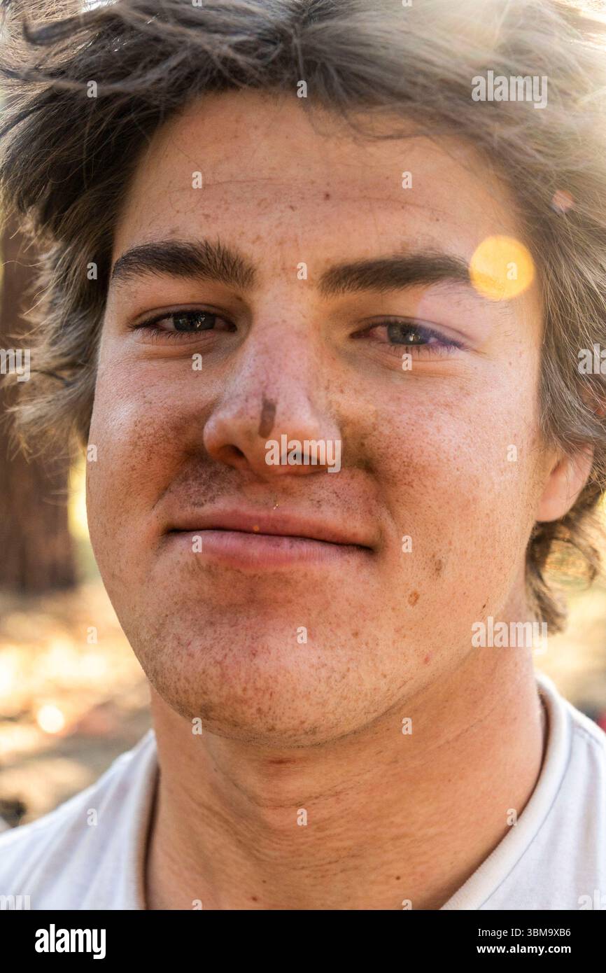 Un dettagliato primo piano di un giovane volto di mans, che mostra varie caratteristiche, e indossa una camicia bianca pulita sulla parte superiore del corpo Foto Stock