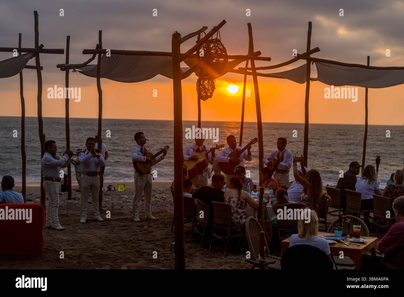 Una band mariachi che suona musica al tramonto in un ristorante sulla spiaggia Playa de los Muertos nella zona romantica di Puerto Vallarta, conosciuta anche come Viejo Foto Stock