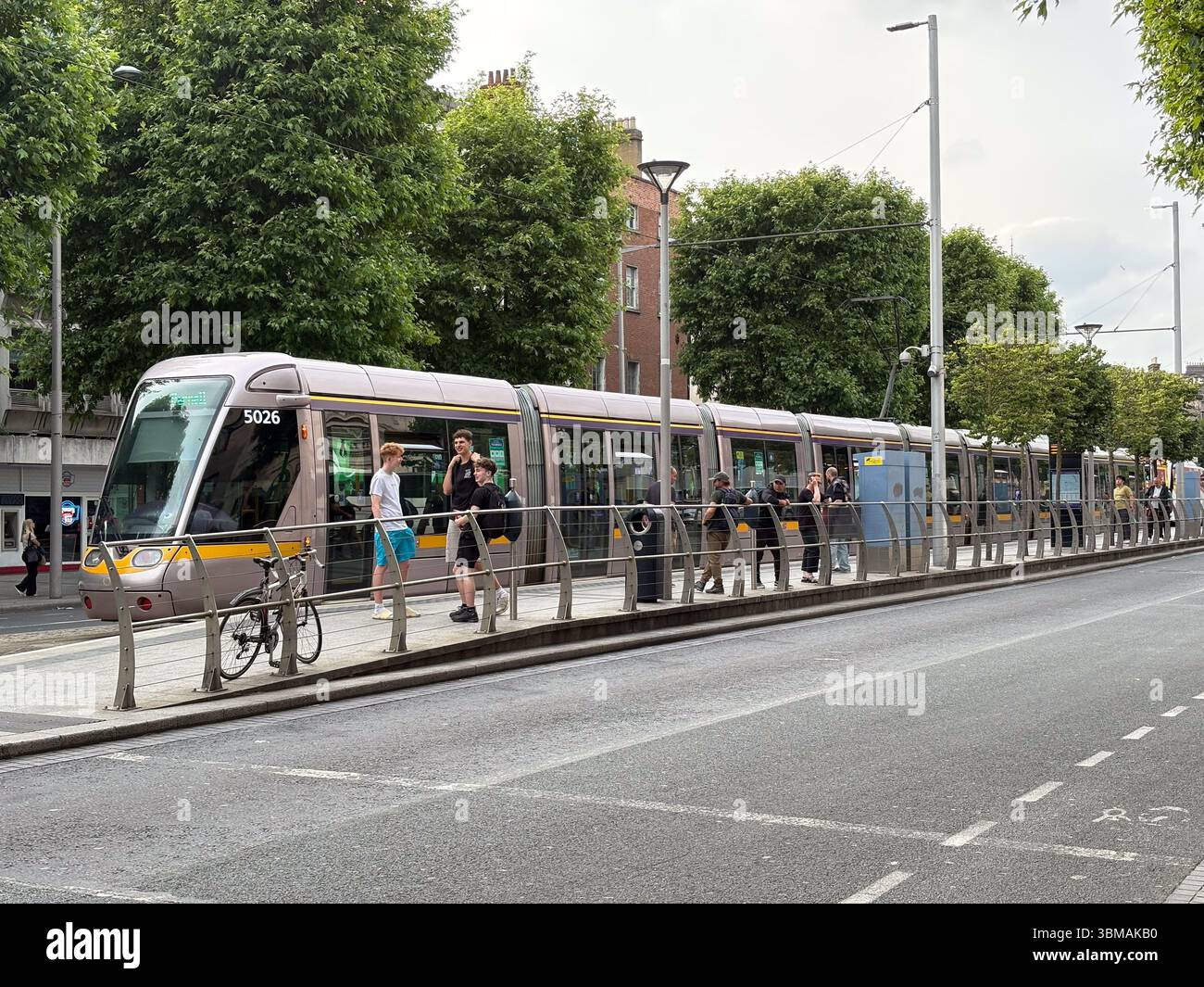 La gente aspetta un tram Luas a una fermata a livello della strada a Dublino, Irlanda. Moderno sistema di trasporto pubblico urbano. Foto Stock