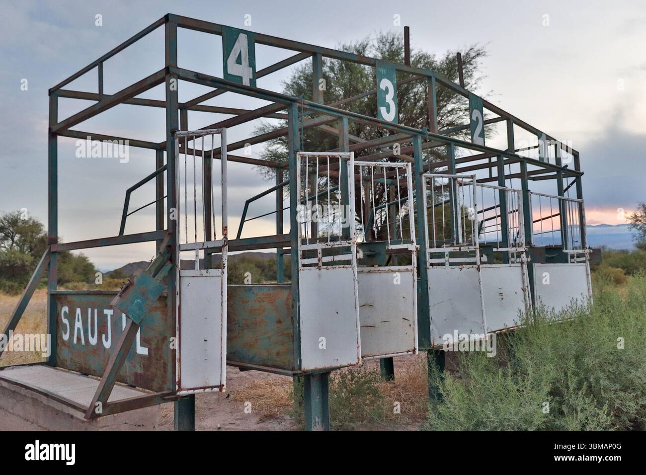 Vecchi cancelli di partenza per cavalli arrugginiti abbandonati a Saujil, Catamarca, vicino a Fiambala, che mostrano gli effetti del tempo in un ambiente rurale. Foto Stock