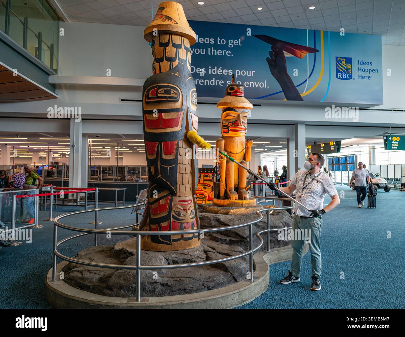 Un operaio spolvera un totem in mostra all'Aeroporto Internazionale di Vancouver. L'aeroporto è noto per la sua collezione di prime Nazioni locali Foto Stock