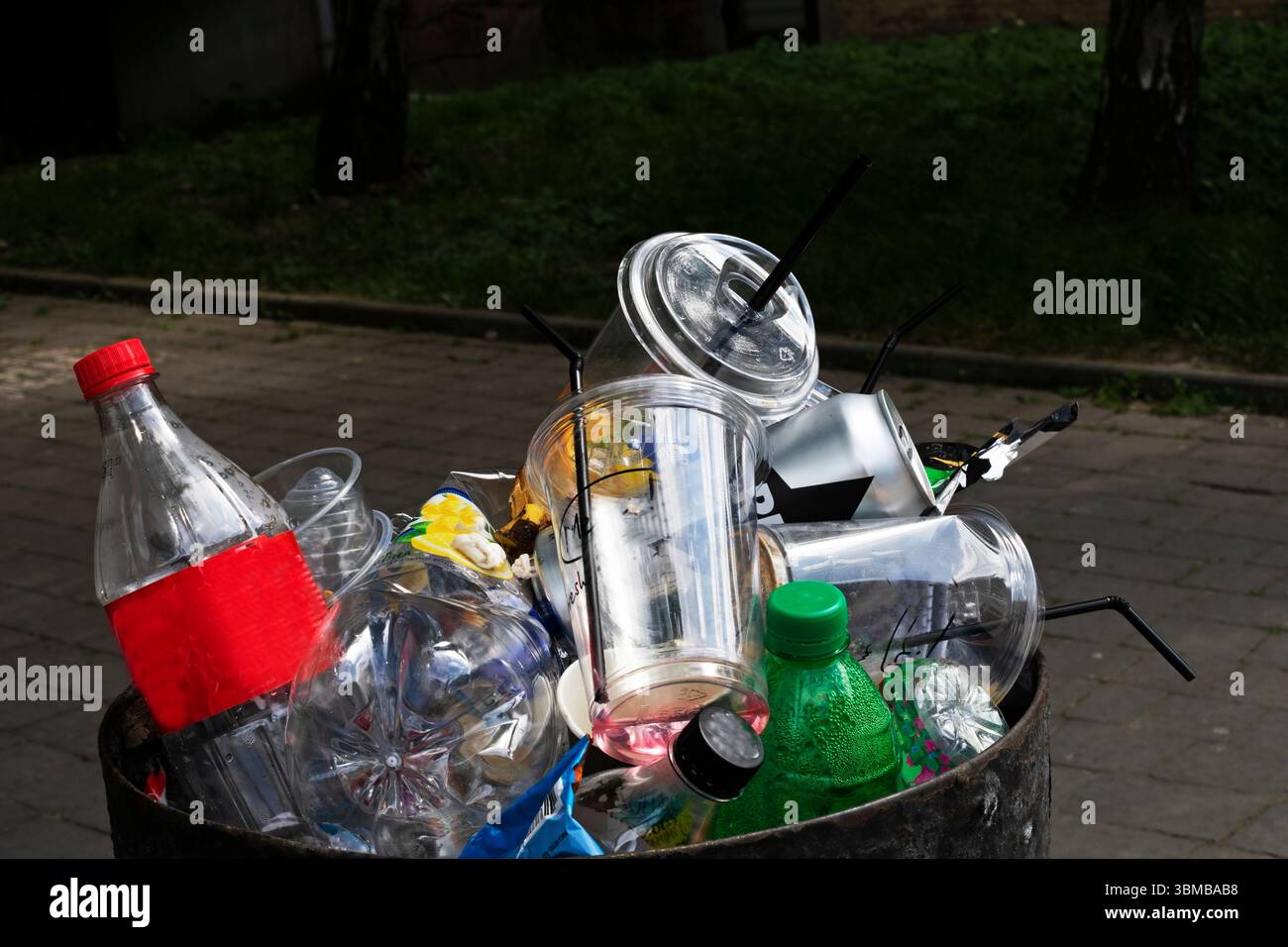 tanica piena di rifiuti lungo la strada con tazze monouso, bottiglie di plastica e altre cose. Protezione dell'ambiente Foto Stock