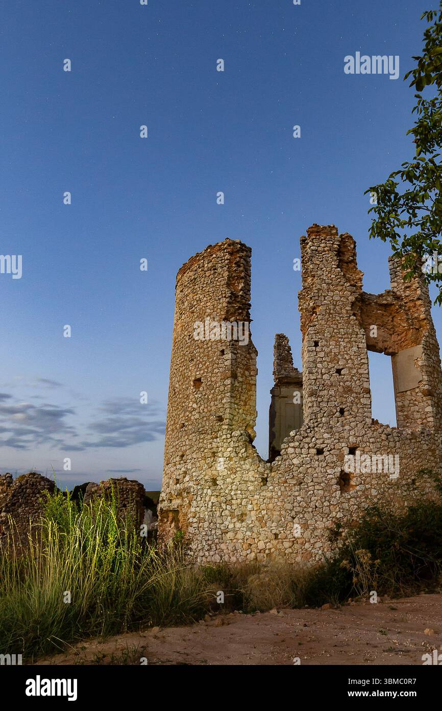 Le rovine di pietra si ergono alte sotto un cielo stellato, circondate dall'erba in un tranquillo ambiente di campagna di notte. Foto Stock