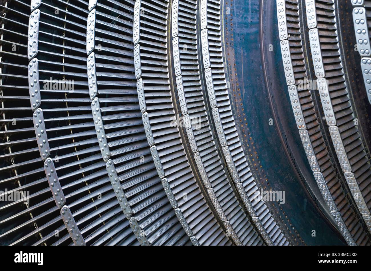 alette e segmenti metallici dettagliati che formano la struttura curva di una turbina industriale o di un componente del motore, mostrando schemi meccanici ripetitivi Foto Stock