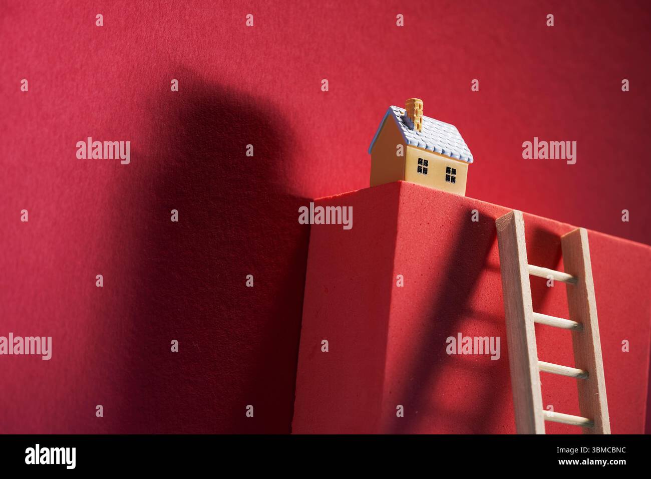 casa modello sulla parte superiore del blocco con scala a pioli appoggiata su di essa. Foto Stock