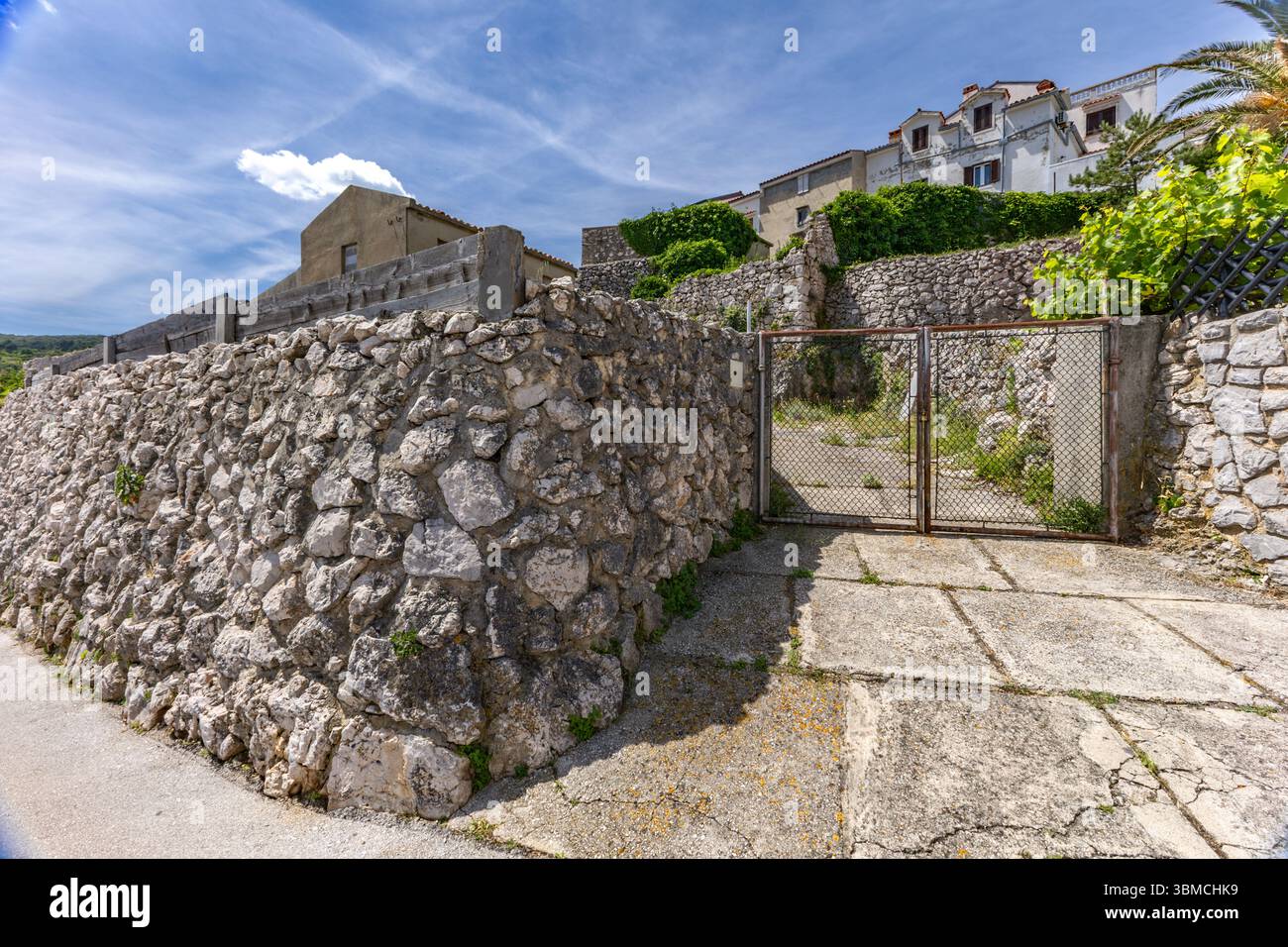 Le mura che circondano la città vecchia di Vrbnik sull'isola di KRK, i monumenti e gli edifici in pietra della città, una passeggiata attraverso le stradine strette Foto Stock