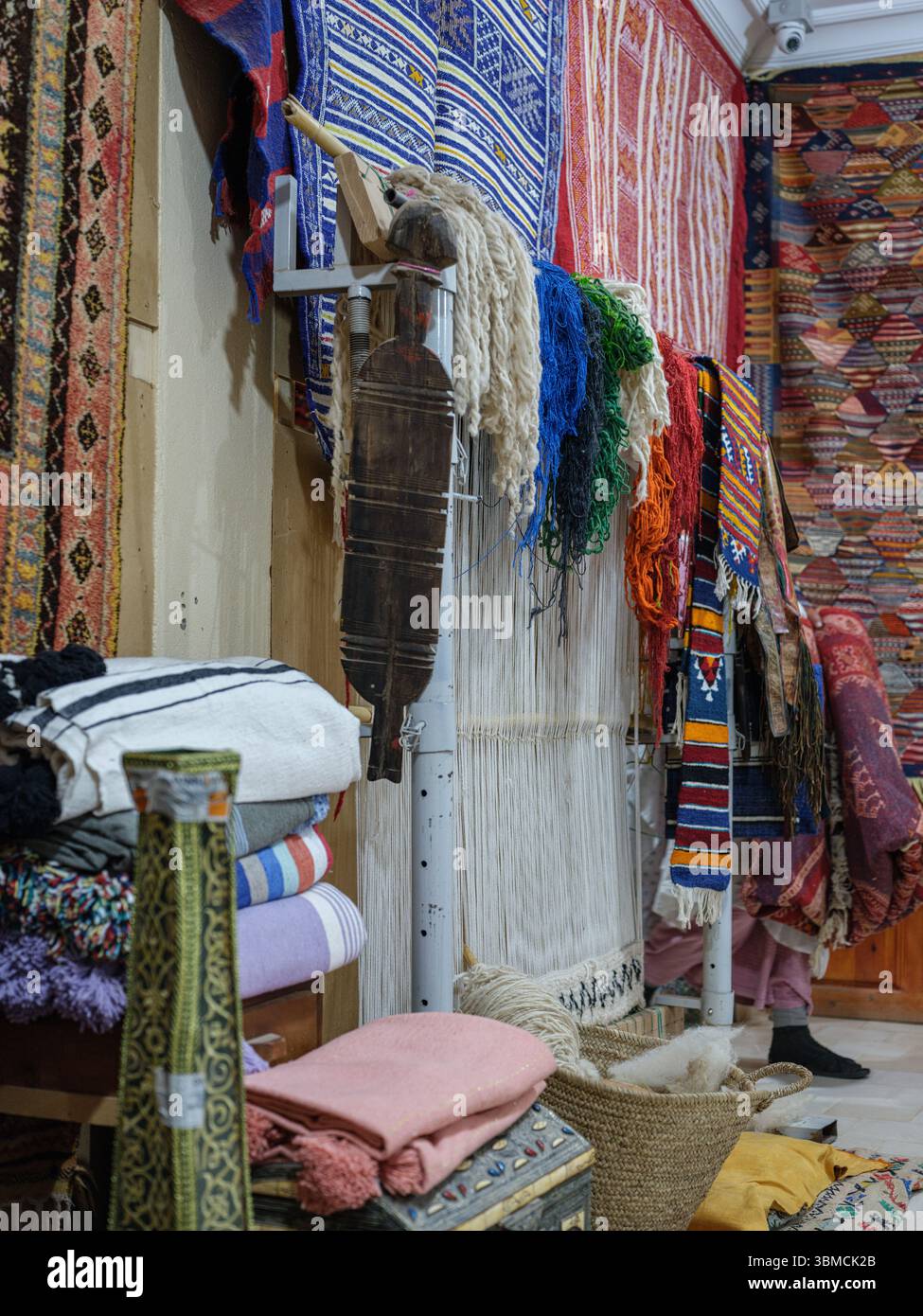 Marocco, Merzouga, 04 luglio 2025. Interno di un tradizionale laboratorio di tappeti berberi nella regione del Sahara, decorato con colorati tappeti e weav fatti a mano Foto Stock