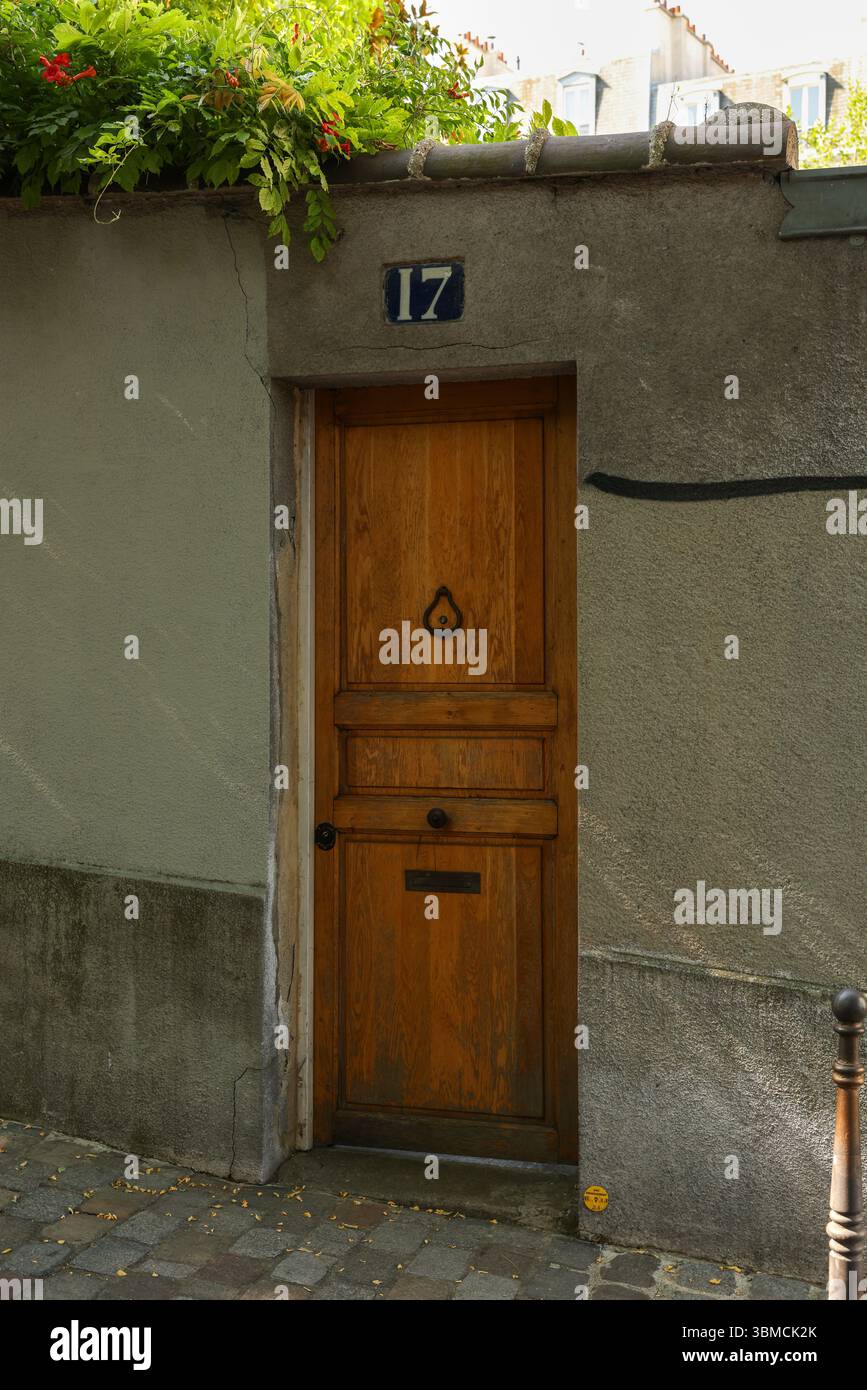 Una fotografia di una vecchia porta rustica in legno su un edificio di Parigi. La porta è marrone con un design semplice ed è caratterizzata da un classico battente. Sopra Foto Stock