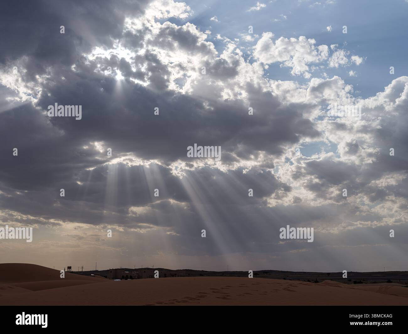 Marocco, Merzouga, 04 luglio 2025. Gli spettacolari raggi del sole che si infrangono attraverso le nuvole sul deserto del Sahara a Erg Chebbi, creando un paesaggio naturale mozzafiato Foto Stock