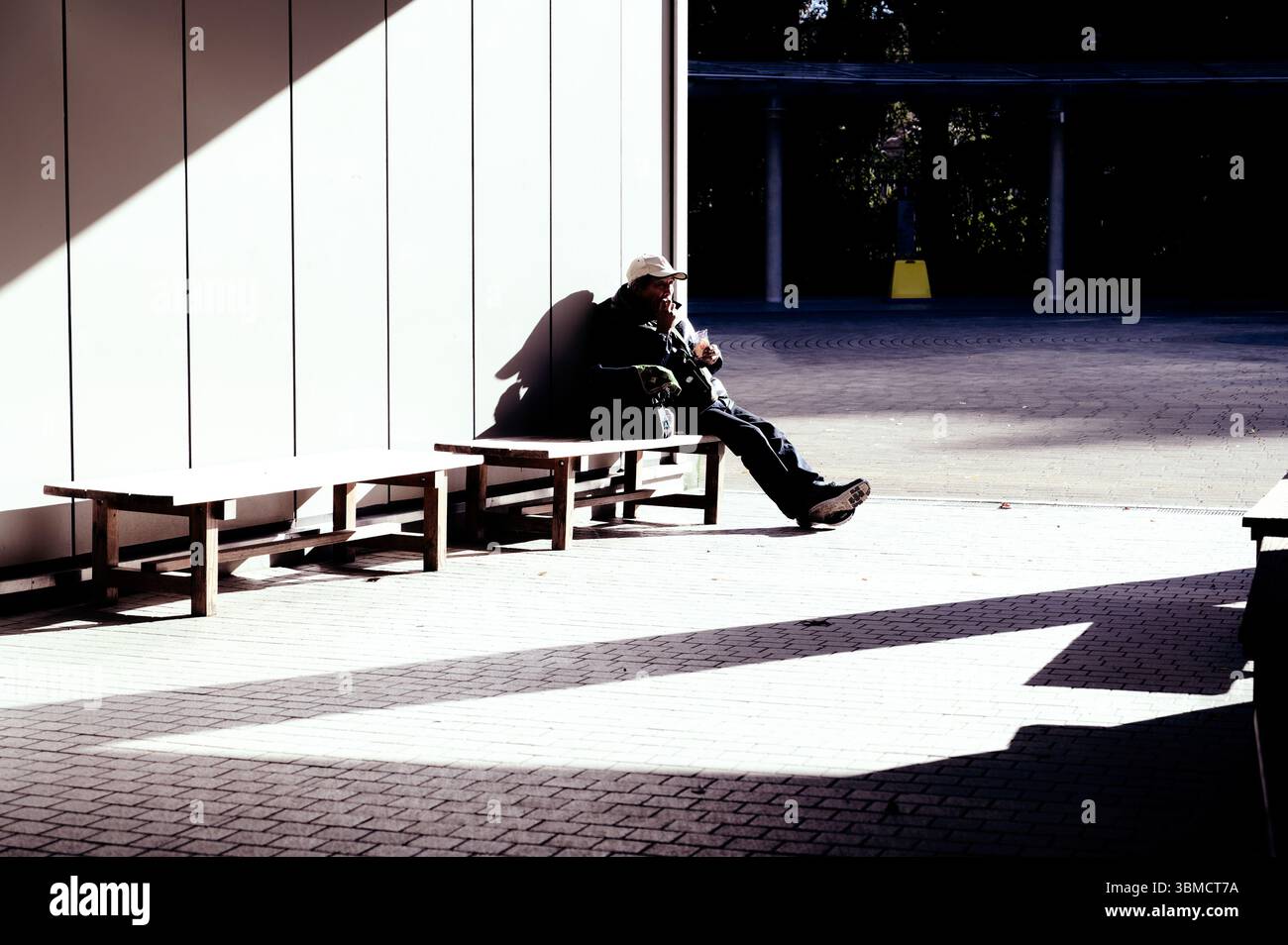 Lavoratore che riposa su una panchina nel parco Yoyogi, immerso nella luce del sole di una giornata invernale Foto Stock