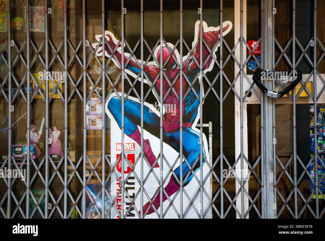 Poster Spiderman visibile dietro una griglia di sicurezza in metallo chiusa di un negozio di fumetti. Foto Stock