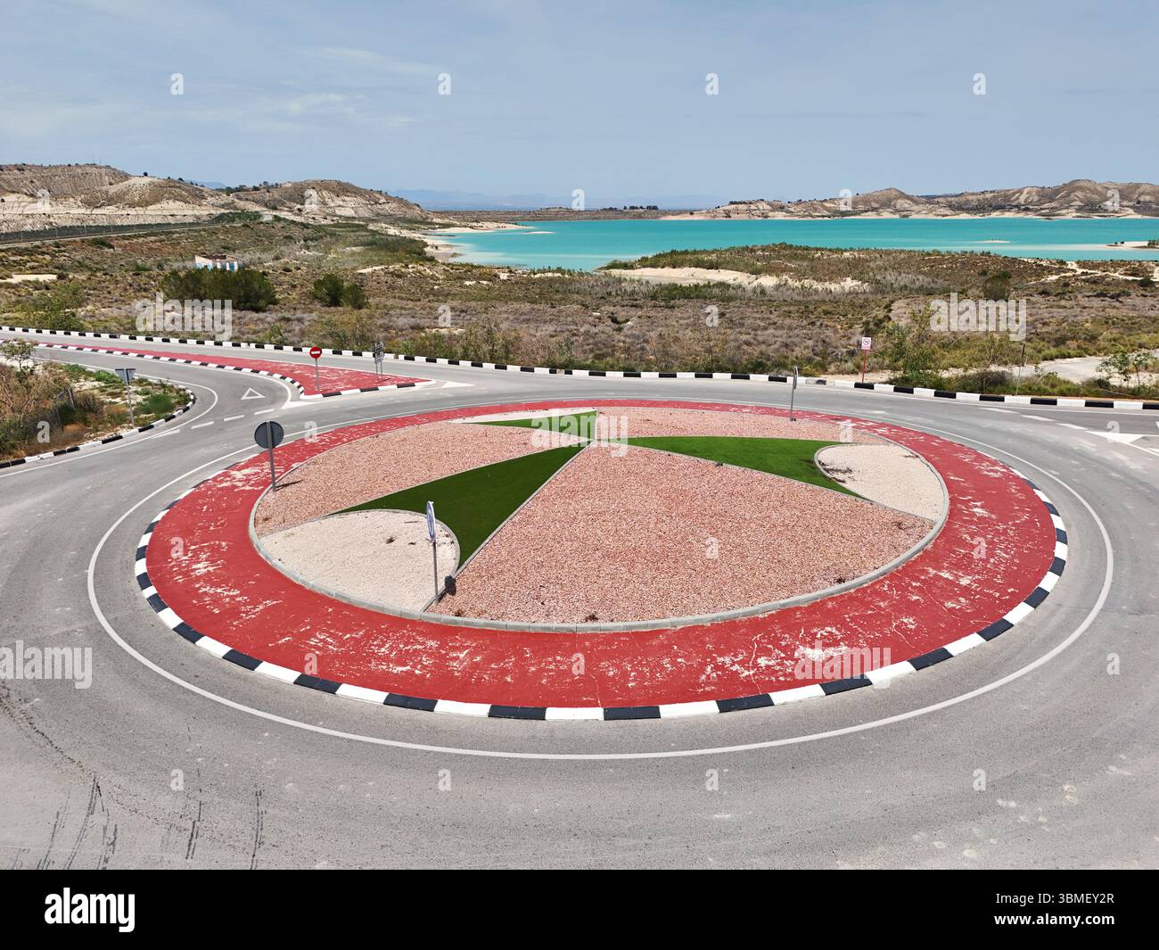 Rotatoria panoramica con paesaggi colorati, moderne segnaletica stradale, situata vicino a un serbatoio turchese di Embalse de la Pedrera. Costa Blanca. Alicante Foto Stock