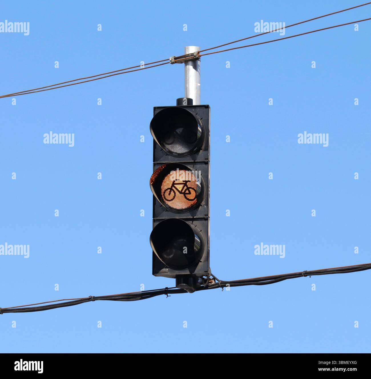 Semaforo giallo per biciclette appese ai fili con il cielo come sfondo. Foto Stock