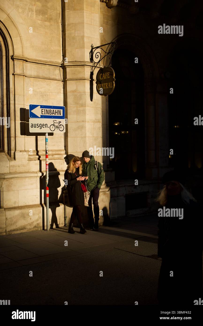 Giovane coppia che insegue gli ultimi raggi di sole in una strada fuori dal famoso Café Central di Vienna a febbraio. Foto Stock