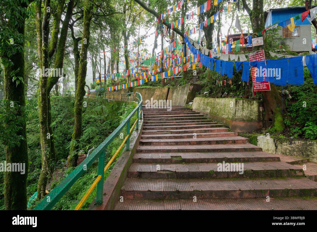 Darjeeling, Bengala Occidentale, India-11.08.2023: Bandiere sulle scale nella foresta, via per il Tempio Mahakal o Mahakal Mandir, tempio indù dedicato al Dio Shiva. Foto Stock
