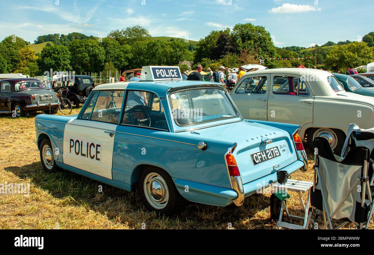Auto della polizia Triumph Herald blu d'epoca esposta ad una mostra di auto d'epoca in una giornata di sole in un paesaggio rurale panoramico Foto Stock