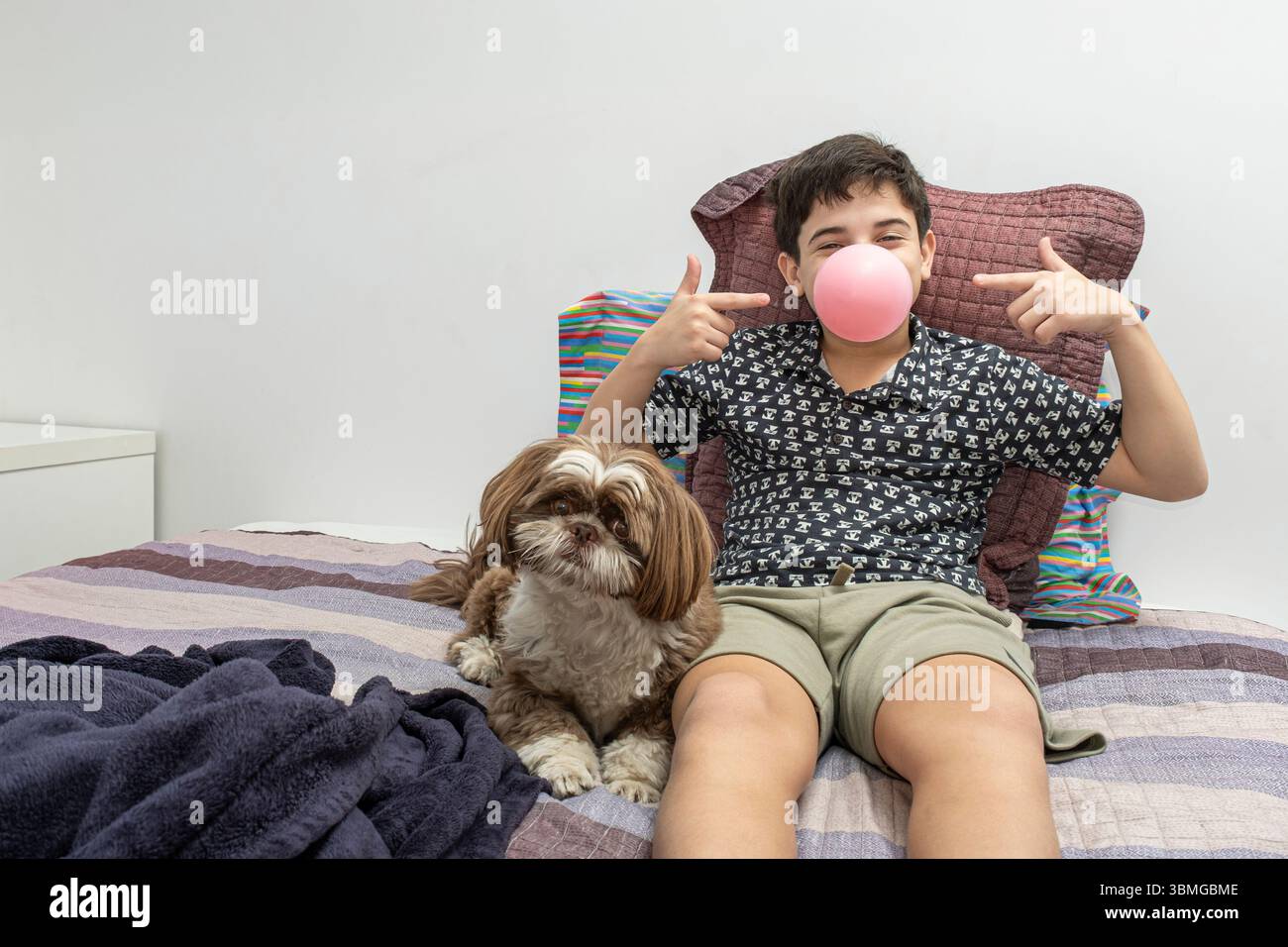 adolescente di 12 anni in piedi accanto al suo cane e che gli indica la gomma in bocca. Foto Stock