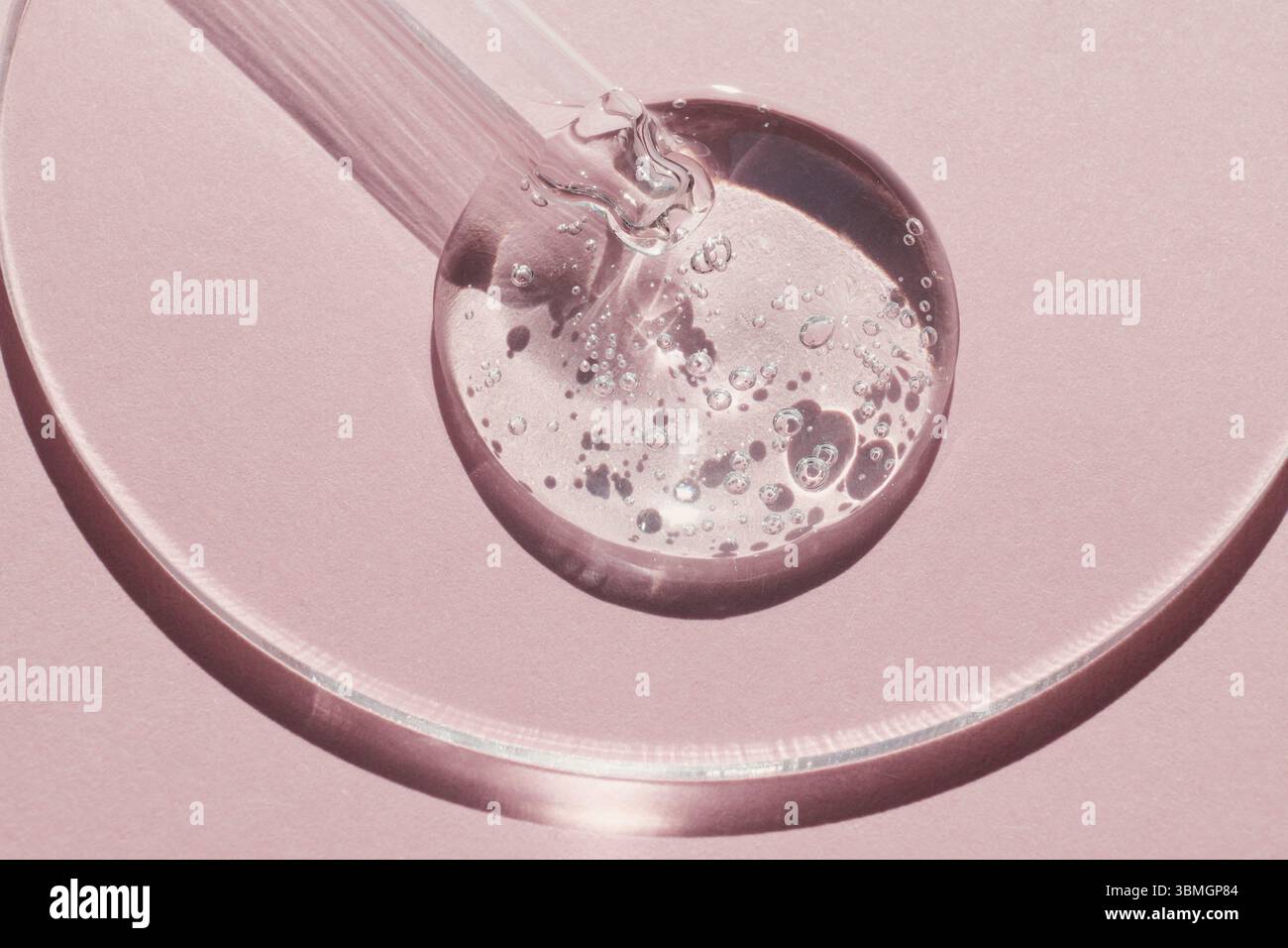 Pipettare con un campione di gel di prodotto cosmetico in capsula di Petri su sfondo rosa, ombre dure Foto Stock