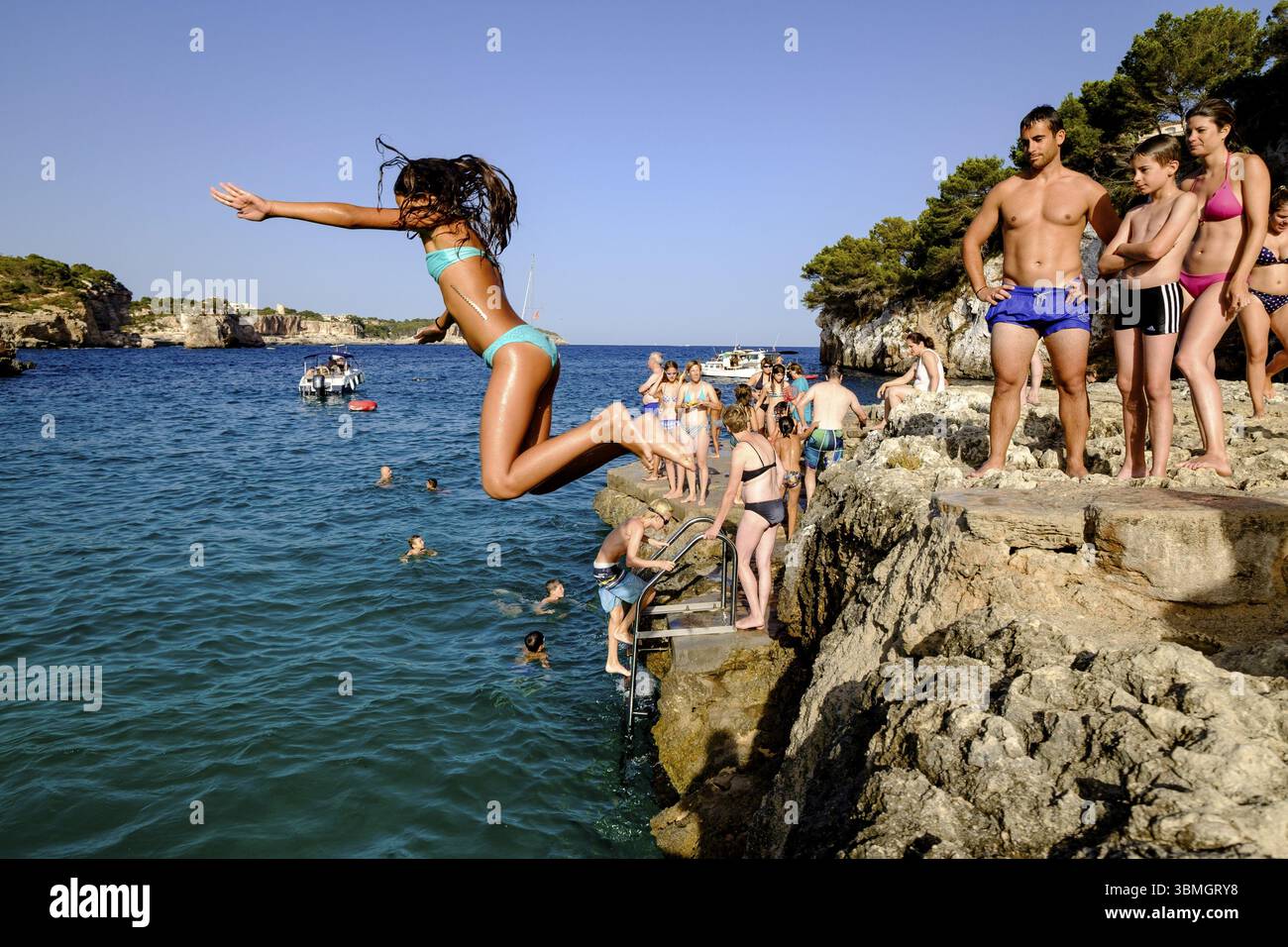 Bagnanti che saltano in acqua, Cala Llombards, Santanyi, Maiorca, Isole Baleari, Spagna, Europa Foto Stock