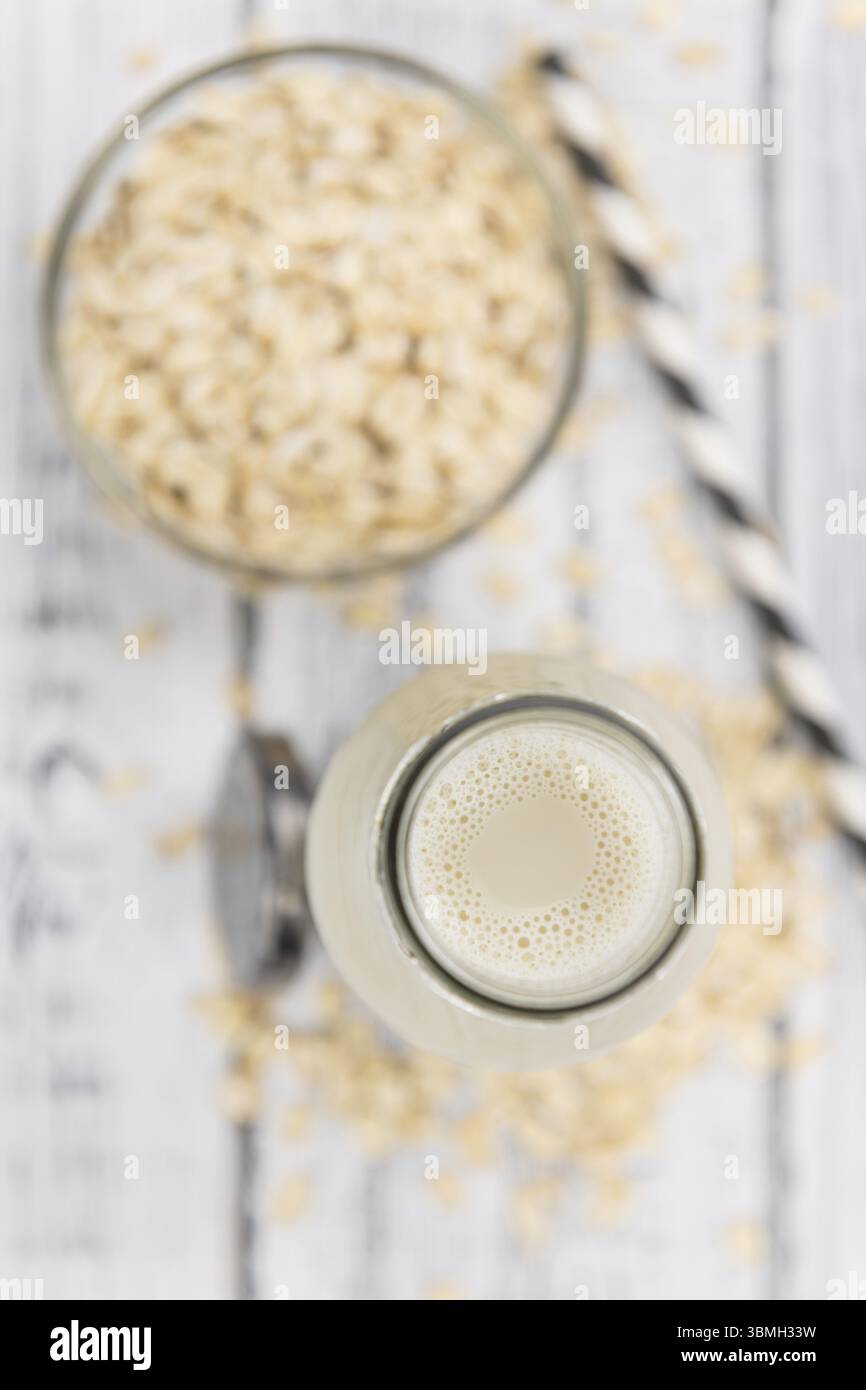 Vecchio tavolo in legno con latte d'avena fresco (primo piano, messa a fuoco selettiva) Foto Stock