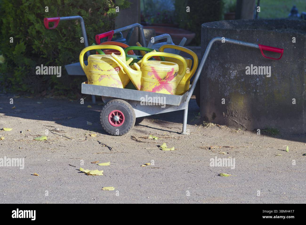 Le lattine in plastica in attesa di essere utilizzate vengono caricate su un carrello manuale in giardino, pronte per l'attività successiva Foto Stock