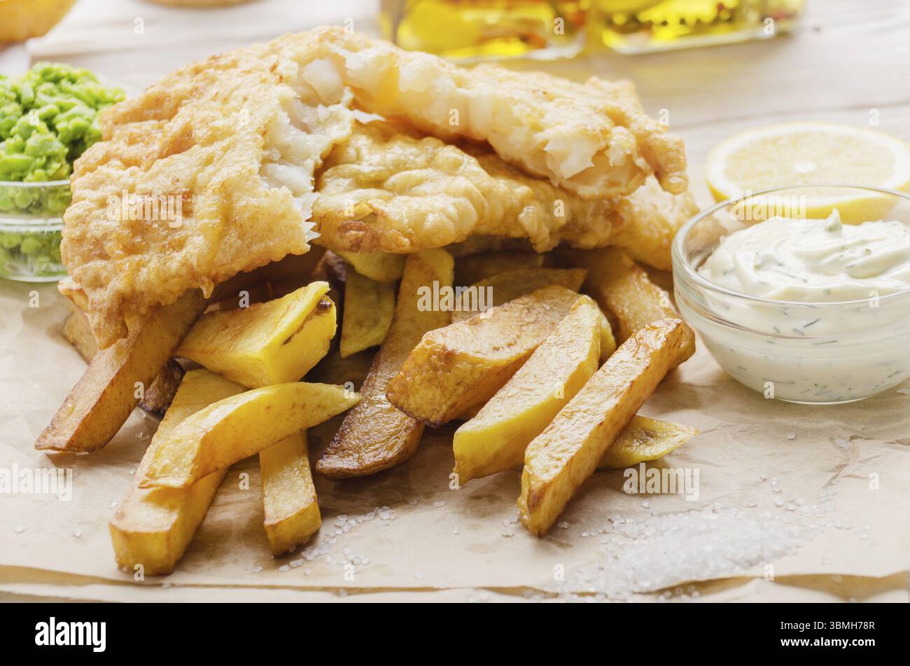 Britannico tradizionale cibo di strada pesce e patatine con salsa tartara e fiacco piselli sul piatto di carta Foto Stock