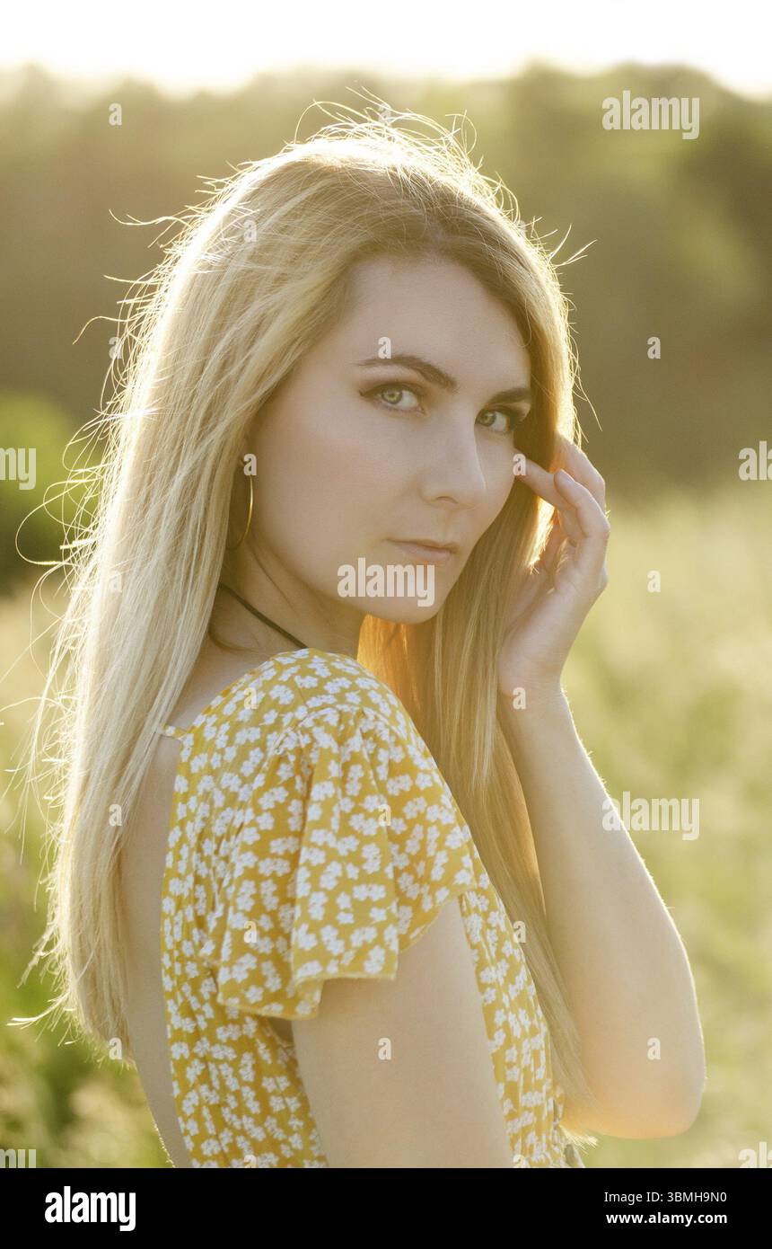 Giovane bionda caucasica modello femminile godendo di attività all'aperto al prato sera estate Foto Stock