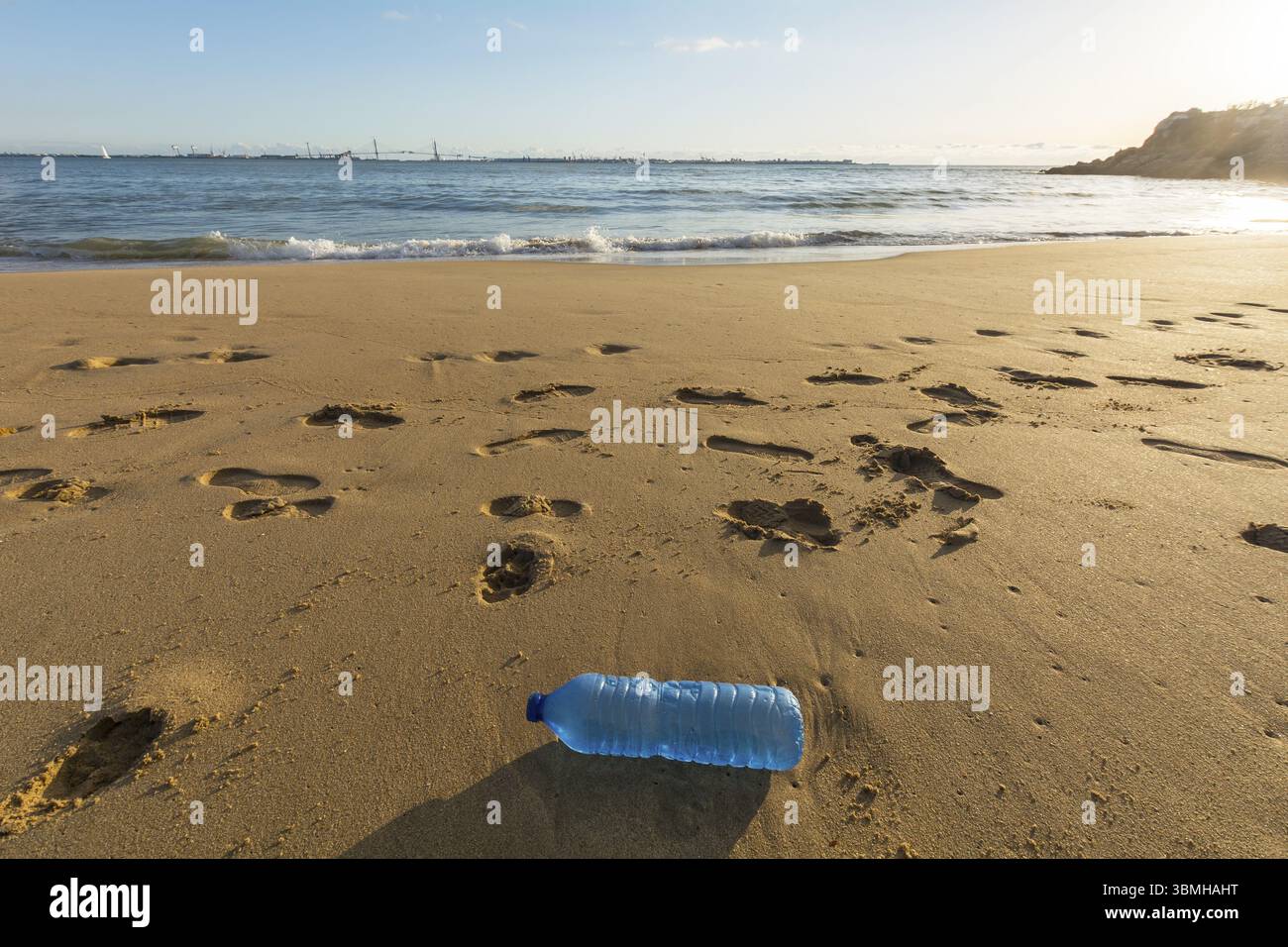Una bottiglia d'acqua gettata sulla riva della spiaggia, inquinamento, spazzatura Foto Stock