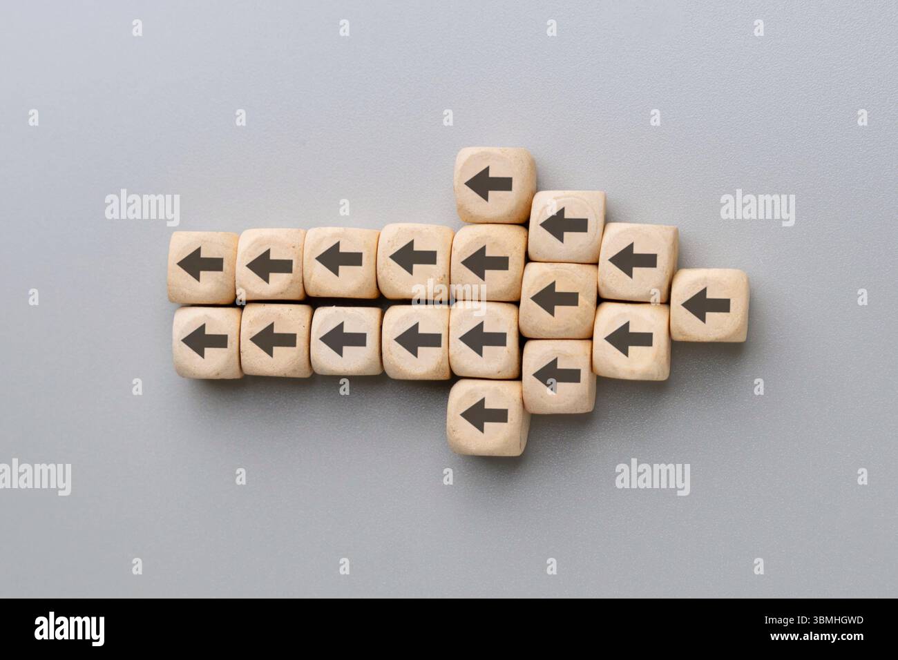 Una grande freccia formata da più blocchi di legno con frecce nere che puntano nella direzione opposta. Resistenza al cambiamento, direzioni in conflitto Foto Stock