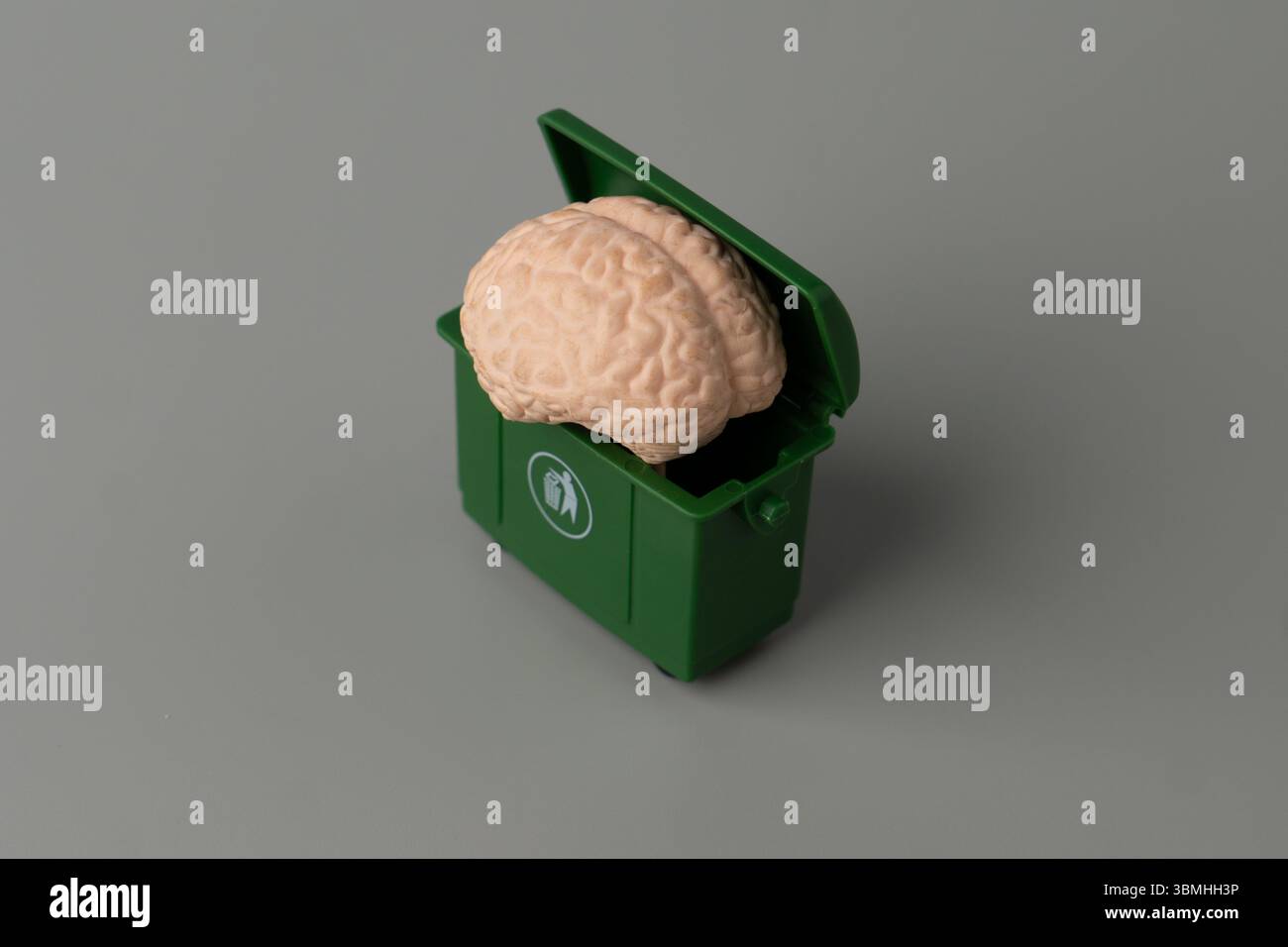 Un modello di cervello umano è collocato all'interno di un cestino. Declino mentale, spreco intellettuale, dimenticanza, fuga di cervelli o scartare idee Foto Stock