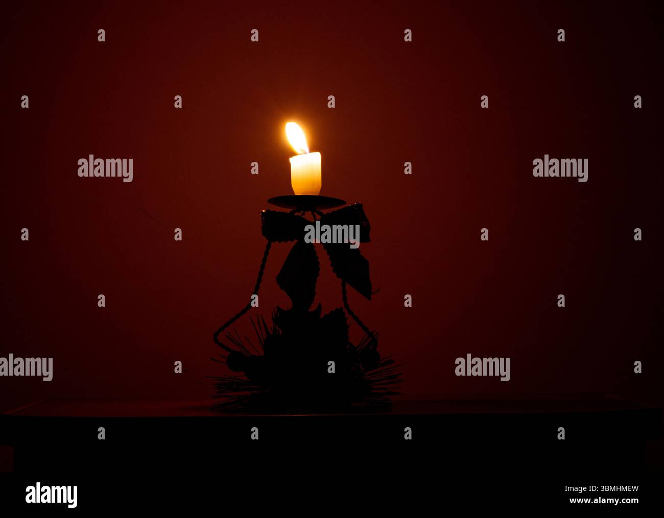 Candela accesa sullo stand di Capodanno con un fiocco al buio, illuminazione natalizia, fiamma di candele, decorazioni natalizie Foto Stock